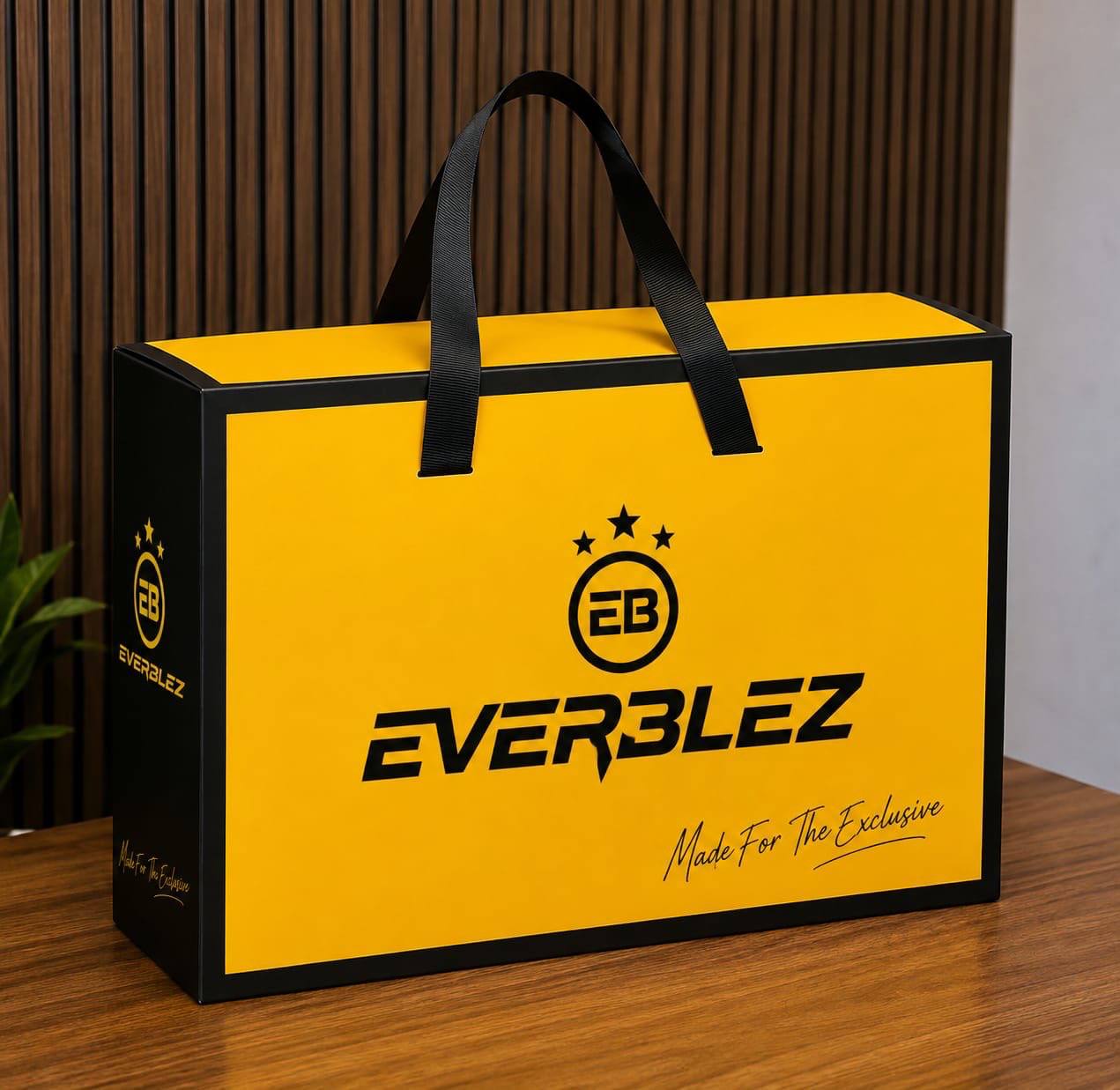 Everblez golden yellow gift box with black ribbon handles and the EB crest